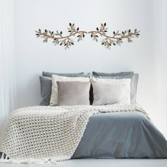 a bed with pillows and blankets on top of it next to a wall hanging above the headboard