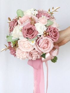 a bride's bouquet with pink and white flowers on it is being held by her hand