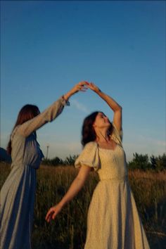 two women standing in a field with their hands together