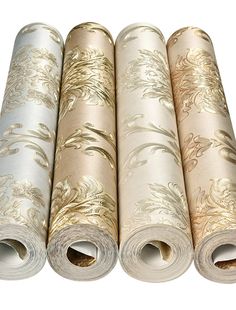 four rolls of wallpaper with gold and silver designs on them, all lined up