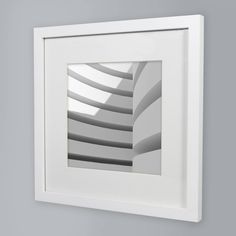 a white frame hanging on the wall with an abstract image in it's center