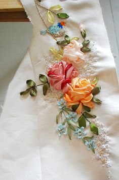 a close up of a dress with flowers on the side and beading around it