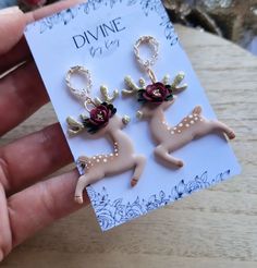 a pair of deer earrings with flowers on it's ears are shown in front of a card