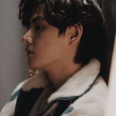 a young man in a fur coat looking off into the distance