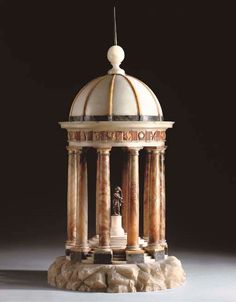 a small white building with columns and a statue in front of it's dome