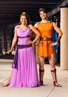 two people in costume standing next to each other on the sidewalk with one person dressed as an orange and purple outfit