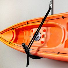 an orange kayak with two oars attached to the front and back ends, hanging on a wall