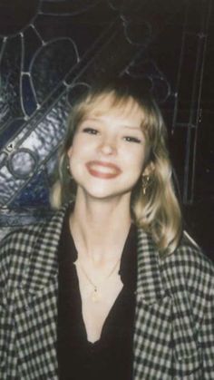 a woman in a black and white checkered jacket smiles at the camera while posing for a photo