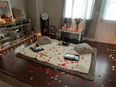 a bed with rose petals on it in a room decorated for valentine's day