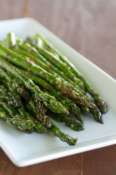 asparagus on a white plate sitting on a wooden table