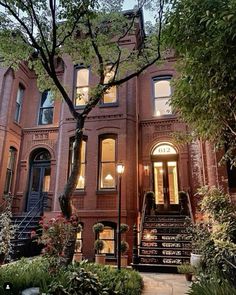 an old brick building with stairs leading up to the front door and trees around it