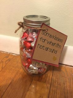 a jar filled with lots of candy sitting on top of a wooden floor next to a wall