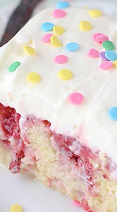 a piece of cake with white frosting and colorful sprinkles