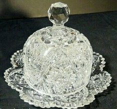 a clear glass butter dish on a black tablecloth with an ornate design around the base