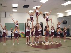 a group of cheerleaders standing on top of each other in the middle of a gym