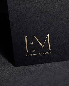 the letter e m is made up of gold foil and black paper with a golden logo