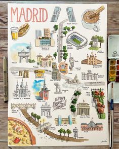 a map of madrid is shown on a piece of paper next to watercolor paints