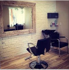 a salon chair sitting in front of a brick wall with a mirror on the wall