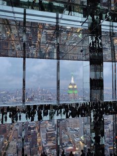 many people are walking on the glass walkway above the cityscape and skyscrapers