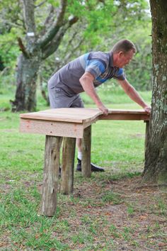 a man is working on a bench in the woods