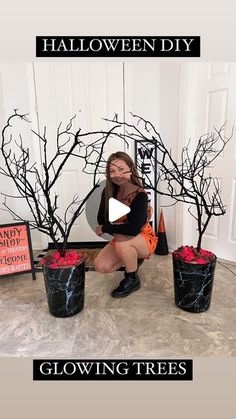 a woman kneeling on the ground next to three black planters with halloween decorations in them