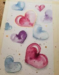 some watercolor hearts on a piece of paper