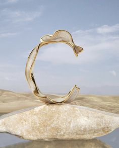 a gold ring sitting on top of a rock in the middle of a desert area