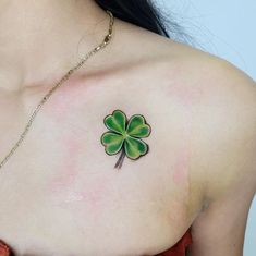 a woman's chest with a four leaf clover tattoo on the left side of her shoulder