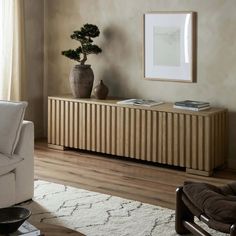 a living room with a couch, chair and potted plant on the sideboard