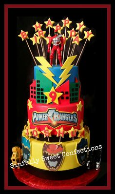 this is a cake decorated with power rangers and stars on the top, as well as an iron man figurine