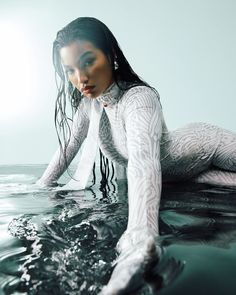 a woman in the water with her hands on her hips and wearing white clothing, posing for a photo