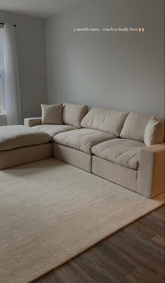 a living room with a large sectional couch in the corner and a rug on the floor