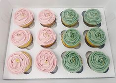 cupcakes with pink and green frosting in a white box on a table