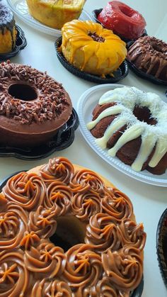 many different types of donuts on plates sitting on a table with frosting and icing