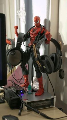 a spider - man figure with headphones on stands in front of a computer