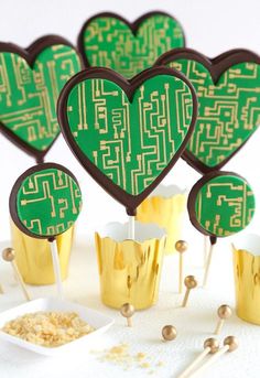 heart shaped cupcakes with green icing and gold foil wrappers on sticks