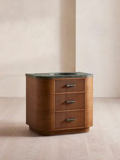 a wooden cabinet with two drawers and a green marble top on the bottom, in front of a beige wall