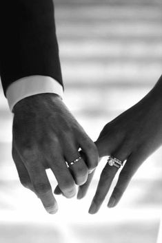 the bride and groom hold hands as they stand close to each other with their wedding rings on their fingers