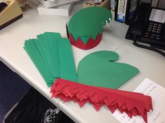 a desk topped with paper cut outs and elf hats