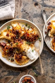 two plates filled with food on top of a stone table next to silverware and napkins