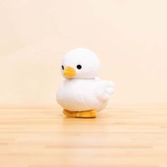 a white duck sitting on top of a wooden floor