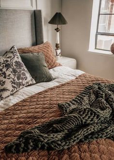 a bed with brown blankets and pillows in a bedroom