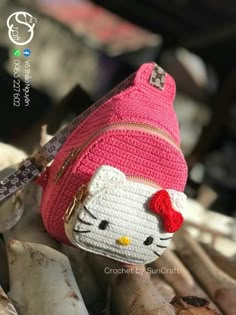 a hello kitty purse sitting on top of a pile of wood next to some branches