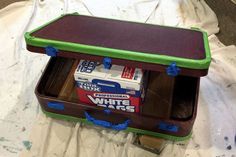 a brown and green case with blue tape around it on top of a white sheet