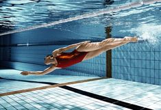 a man in a red swimsuit dives into a swimming pool