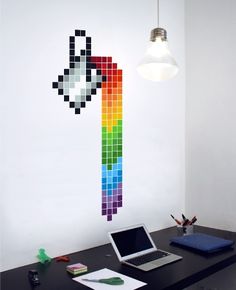 a laptop computer sitting on top of a desk next to a pixel wall decal