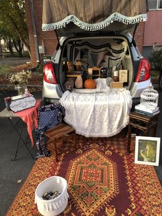 the trunk of a car is open with various items in it and on top of a rug