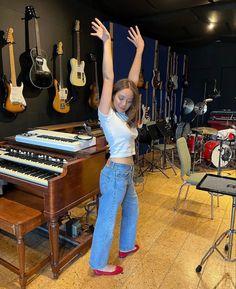 a woman standing in front of a keyboard with her arms up and hands above her head