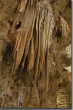 the cave is filled with stalate formations and hanging from the ceiling, making it look like they are floating in water