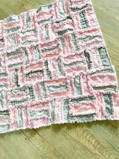 a close up of a piece of cloth on a wooden floor with a pink and gray pattern